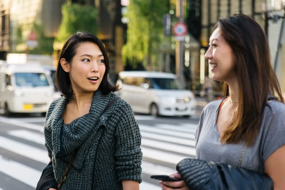 Two women chatting on a busy singapore street, showcasing the cultural vibrancy of the city. Their animated expressions reflect the complexities of communication, mirroring the challenges ai like notebooklm faces in understanding singlish—a creole language rich in context and cultural nuances